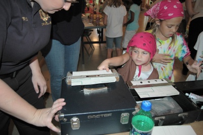 Crime laboratory technician Summer Porter demonstrates fingerprinting to girl scouts at a CSM criminal justice program in September.