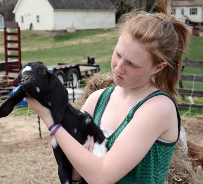 Jacqueline Bowen, 14, who helps run the Green Goats business with her mother Mary, holds a baby goat. Jacqueline is in charge of naming every goat born to the family's herd, and says every name is a reflection of each goat's personality. (Photo: Patrick Farrell)