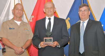 Jack Bernardes (center) holds the Dahlgren Award plaque after he was presented the award and congratulated by Capt. Brian Durant, Naval Surface Warfare Center Dahlgren Division (NSWCDD) Commander, and Dennis McLaughlin, NSWCDD Technical Director at the command's annual Honor Awards Ceremony. Bernardes - honored for his leadership and technical work supporting the Navy's Railgun Program - led the efforts to establish a world-class electromagnetic launch laboratory capable of firing projectiles at muzzle energies exceeding 32 mega joules. (U.S. Navy photo/Released)