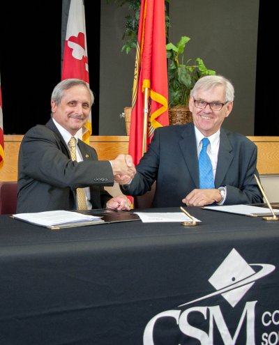CSM President Bradley Gottfried (left) and St. Mary’s College Interim President Ian Newbould (right) shake hands after signing a transfer agreement to guarantee admission of qualified CSM graduates to complete their four-year degrees at St. Mary’s College. (Submitted photo)