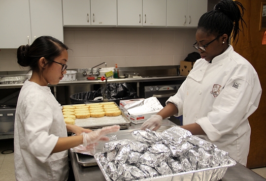 North Point High School culinary arts students Cayezel Balbonado, a junior, left, and Akira Moss, a senior, wrap garlic bread before dinner at Our Place soup kitchen in Waldorf.