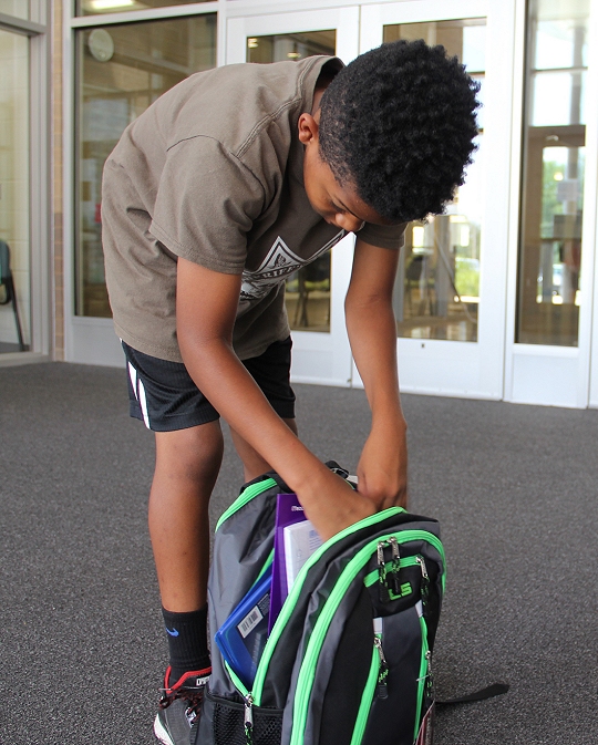 Isaiah Teasley, a sixth grader at Matthew Henson Middle School, looks through the new backpack he and other campers received at Youth Achievement Camp. The backpack was filled with school supplies.