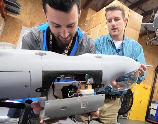 Navy scientist Jordan Lieberman, left, works with engineer Jonathan Crook to install the SCAPEGOAT payload onto a Boeing Insitu Scan Eagle unmanned aerial vehicle (UAV) prior to a system test flight. The SCAPEGOAT system - which includes modular interfaces to multiple chemical, biological, and radiological sensors and UAV platforms - was developed by junior scientists and engineers engaged in the Naval Surface Warfare Center Dahlgren Division sponsored Sly Fox Program over a six-month period.