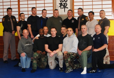 Sheriff Rex Coffey, Major Joseph “Buddy” Gibson and instructors at the Southern Maryland Jujitsu Academy celebrate success of the thirteen defensive tactics graduates.