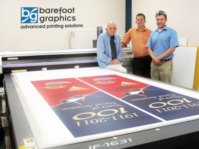 Barefoot Graphics' newly acquired UV flatbed printer after having completed 300+ double sided pole banners for the 100 Yrs. of Naval Aviation celebration. (Pictured L to R - Harry J. Frauenfelder III, Harry J. Frauenfelder IV, and Harry J. Frauenfelder V "Josh")