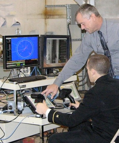 A U.S. Naval Academy midshipman tracks an imagery target while controlling the gun console for the Surface Warfare Mission Module (SWMM) that includes two 30mm Gun Mission Modules (GMM) at NSWC Dahlgren Nov. 19. Meanwhile, a Navy civilian SWMM engineer provides guidance, explaining how the Gun Mission Module operates. The modular weapon system can be easily changed out to facilitate incorporation of future technologies that many midshipmen will see when they are Littoral Combat Ship (LCS) crew members. SWMM replaces a traditional fixed weapon system that was permanently installed on ships such as the AEGIS DDG. The GMM is an integral part of the LCS which will be used for counter-piracy, maritime interdiction and security missions.