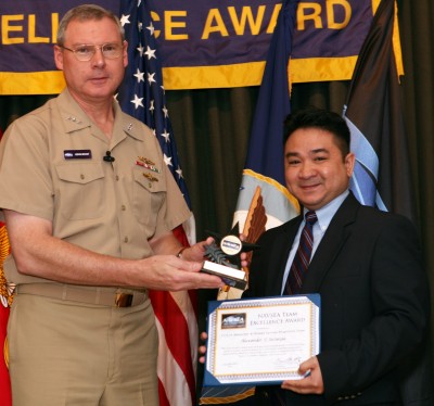 Vice Adm. Kevin McCoy, commander, Naval Sea Systems Command, presents the NAVSEA Excellence Award to NSWC Dahlgren Human Systems Integration (HSI) engineer Alex Salunga - accepting the award on behalf of the six-member NSWC Dahlgren HSI team - at a Washington D.C. ceremony Dec. 7. The Dahlgren HSI engineers were honored for their superior support to the CVN 78 (Gerald R. Ford next generation carrier) Program as key players in the Warfare System Engineering Technical Team. Capitalizing on the investment made while assessing the Ford class of nuclear aircraft carriers, the team applied findings to the USS Nimitz (CVN-68) class of nuclear aircraft carriers - achieving manpower reductions of 25 percent, resulting in a savings of $17.7 million.