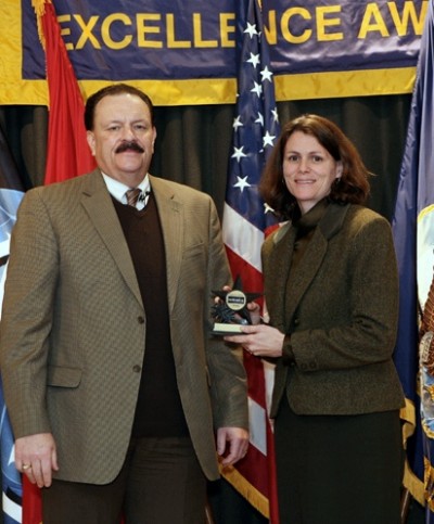 Naval Sea Systems Command Executive Director Brian Persons presents the NAVSEA Excellence Award to Nancy Haymes, an Acquisition Engineering Agent from Naval Surface Warfare Center Dahlgren Division (NSWCDD) at a ceremony held in Washington D.C. Dec. 11. Haymes was one of 37 NSWCDD employees serving on teams honored for excellence in their contributions to the Navy. (Photo: U.S. Navy)