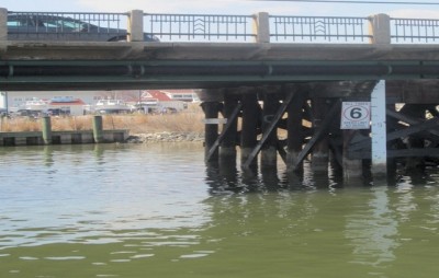 Measuring rods mark water levels under a bridge in Chesapeake Beach. In low-lying coastal areas, high tides sometimes prevent charter boats from clearing bridges and flood roadside ditches. (Photo: Sydney Paul)