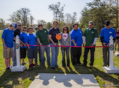 Commissioner Ken Robinson (District 1) (center, holding disc) and Chief of Parks Tom Roland (second from left) help to cut the ribbon officially opening the new Turkey Hill Disc Golf Course in La Plata.