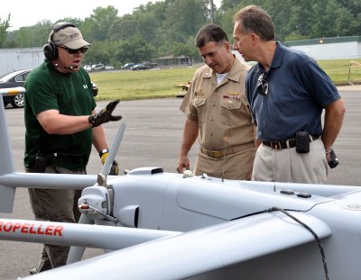 Donn Rushing, left, crew chief for the Unmanned Aerial Systems Test Directorate, briefs Capt. Pete Nette, center, commanding officer of Naval Support Activity South Potomac, and Nelson Mills, right, senior engineer at the Naval Surface Warfare Center Dahlgren Division, about the Aerostar UAS in the foreground during testing May 21. The planning phase of the test required extensive coordination with between Dahlgren-based commands, Naval Air Systems Command and the FAA. (U.S. Navy photo by Andrew Revelos/Released)