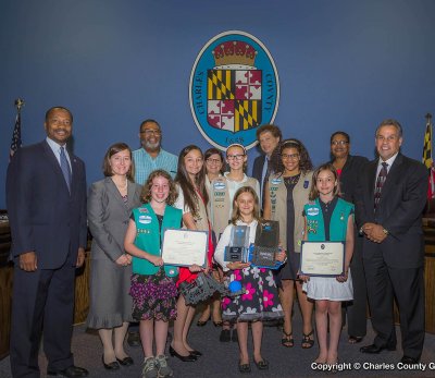 Pictured (left to right), Commissioner Vice President Reuben B. Collins, II (District 3); Jennifer Gerstman (troop #5064 leader); Rachel Brasch; Elliot Simmons (coach); Abigail Gerstman; Commissioner President Candice Quinn Kelly; V; Sophia Gerstman; Commissioner Ken Robinson (District 1); Olivia Simmons; Elizabeth Gerstman ; Commissioner Debra Davis Esq. (District 2); and Commissioner Bobby Rucci (District 4).