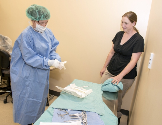 College of Southern Maryland Veterinary Assistant Program lab instructor Meg Hamilton, back, looks on as student Regina Baker practices sterile gowning and gloving techniques. The first of five courses in the 10-month program begins Aug. 23.