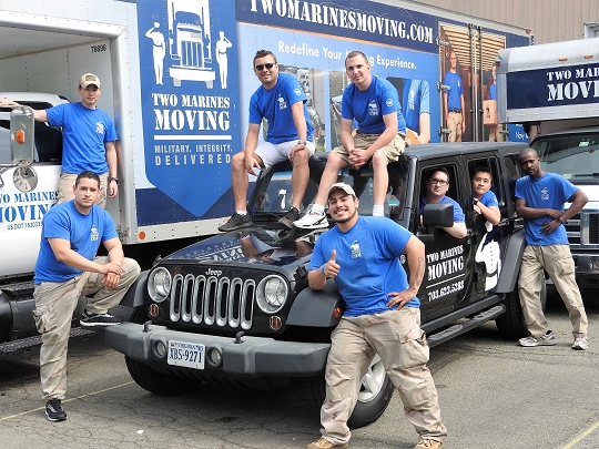 Some of the Two Marines Moving staff pose for a group shot with a few of their vehicles.