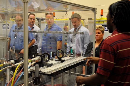 DAHLGREN, Va. - Navy aerospace engineer Roger Campbell (right) briefs Electromagnetic Maneuver Warfare (EMW) Systems Engineering and Acquisition Conference attendees on the high energy laser lethality lab, Sept. 22. The Naval Surface Warfare Center Dahlgren Division (NSWCDD) laser lethality lab has 44 kilowatt laser capability for vulnerability testing and an indoor 100 meter laser tunnel. NSWCDD co-hosted the conference in partnership with the Association of Old Crows. More than 200 attendees - including experts from the Department of Defense, private industry, military and academia - were engaged in discussions covering defense acquisition, mission engineering, electromagnetic maneuver, and electronic warfare systems. (U.S. Navy photo by Luefras Robinson/Released)