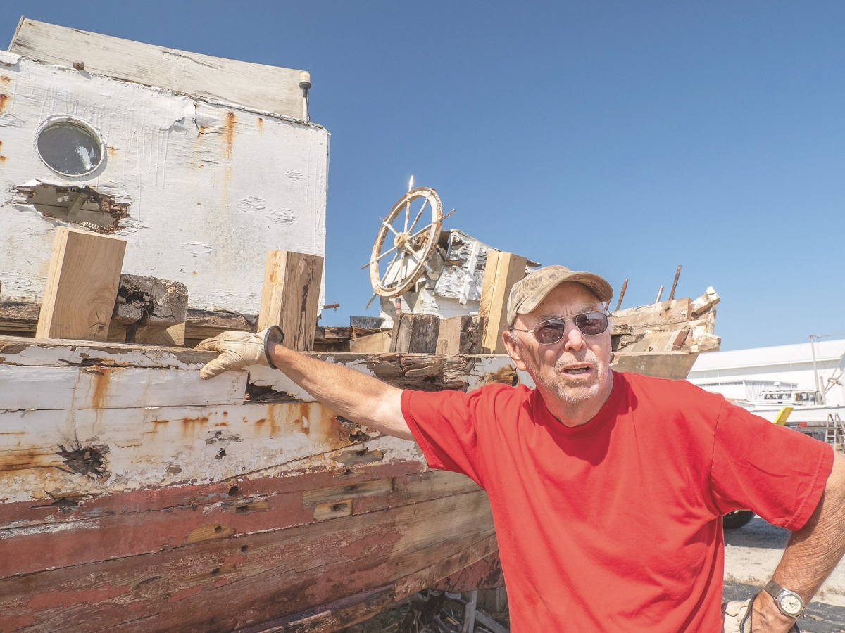 The City of Crisfield, a skipjack once captained by the late Art Daniels Jr., rests on land at a boatyard on Deal Island, Md. where Bob Fitzgerald (pictured) is conducting restoration work. (Bay Journal photo by Dave Harp)