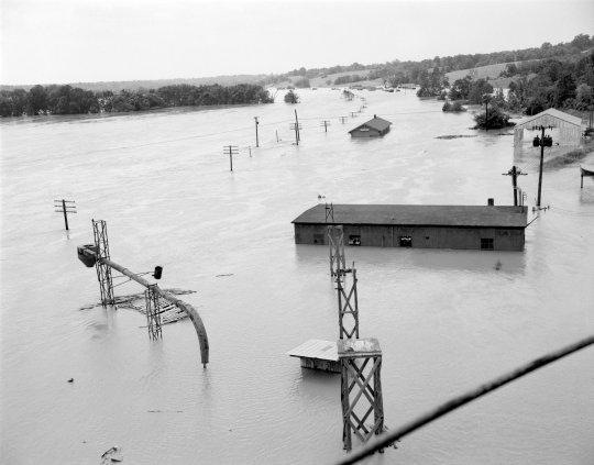 A post-Agnes aerial view of Cartersville, VA, on the James River about 25 miles from Richmond. The flood destroyed the Route 45 Cartersville Bridge, built in 1884, carrying away its four center spans. The two shoreside spans of the bridge still stand beside a new bridge and are preserved as historical sites. (Library of Virginia, via Flickr Commons)