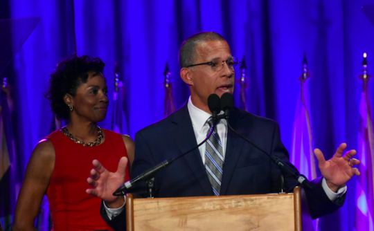 Democratic Rep. Anthony Brown gives his acceptance speech on Election Night to a crowded room of Democratic supporters at the Baltimore Marriott Waterfront. Brown is supported on stage by his wife. Karmen Brown. (Shannon Clark/Capital News Service)